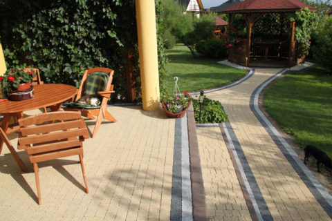 Terrasse en bois et allée pavée menant à un kiosque de jardin